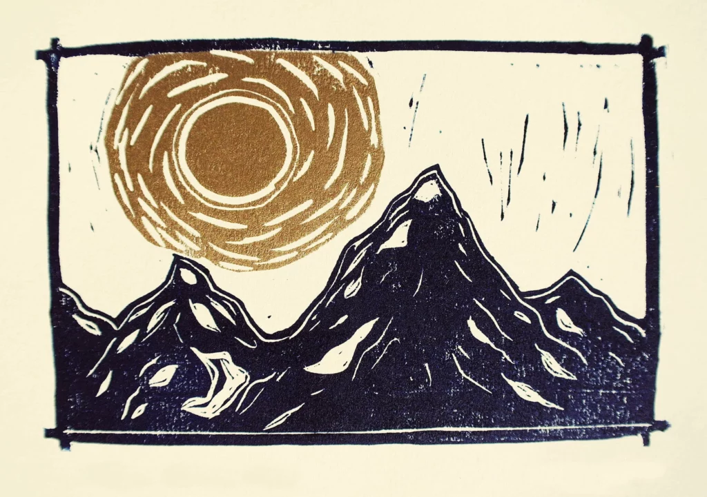 A lino print with a vibrant golden sun over black mountians made by local artist Maya Dudok